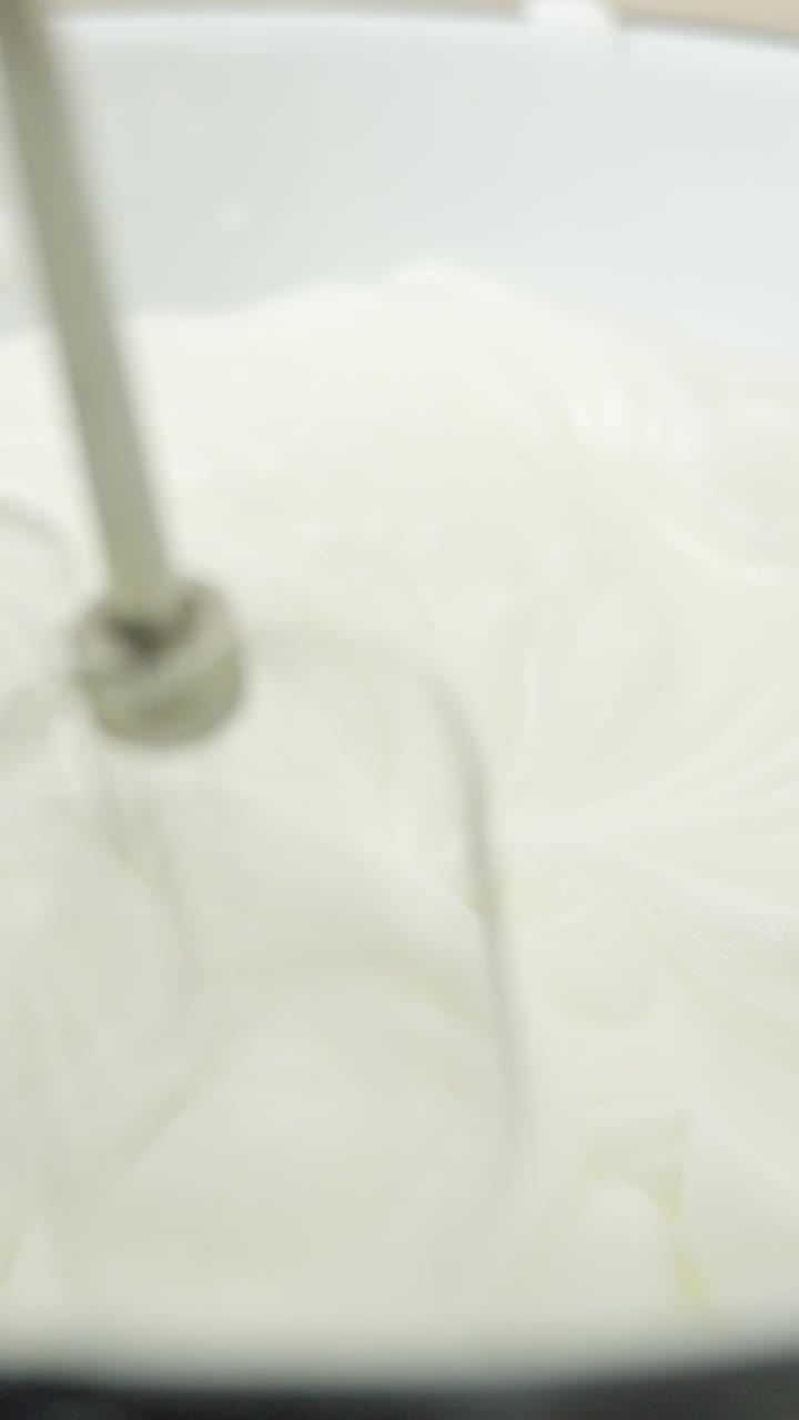 Close-up vertical shot of egg whites being mixed to fluffy peaks for creamy tiramisu layers.