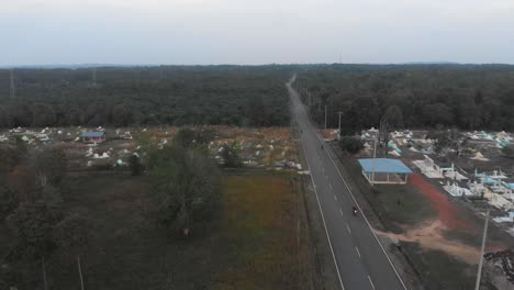 Volando-Sobre-La-Carretera-Local-Con-Cementerio-En-Indonesia,-Aéreo