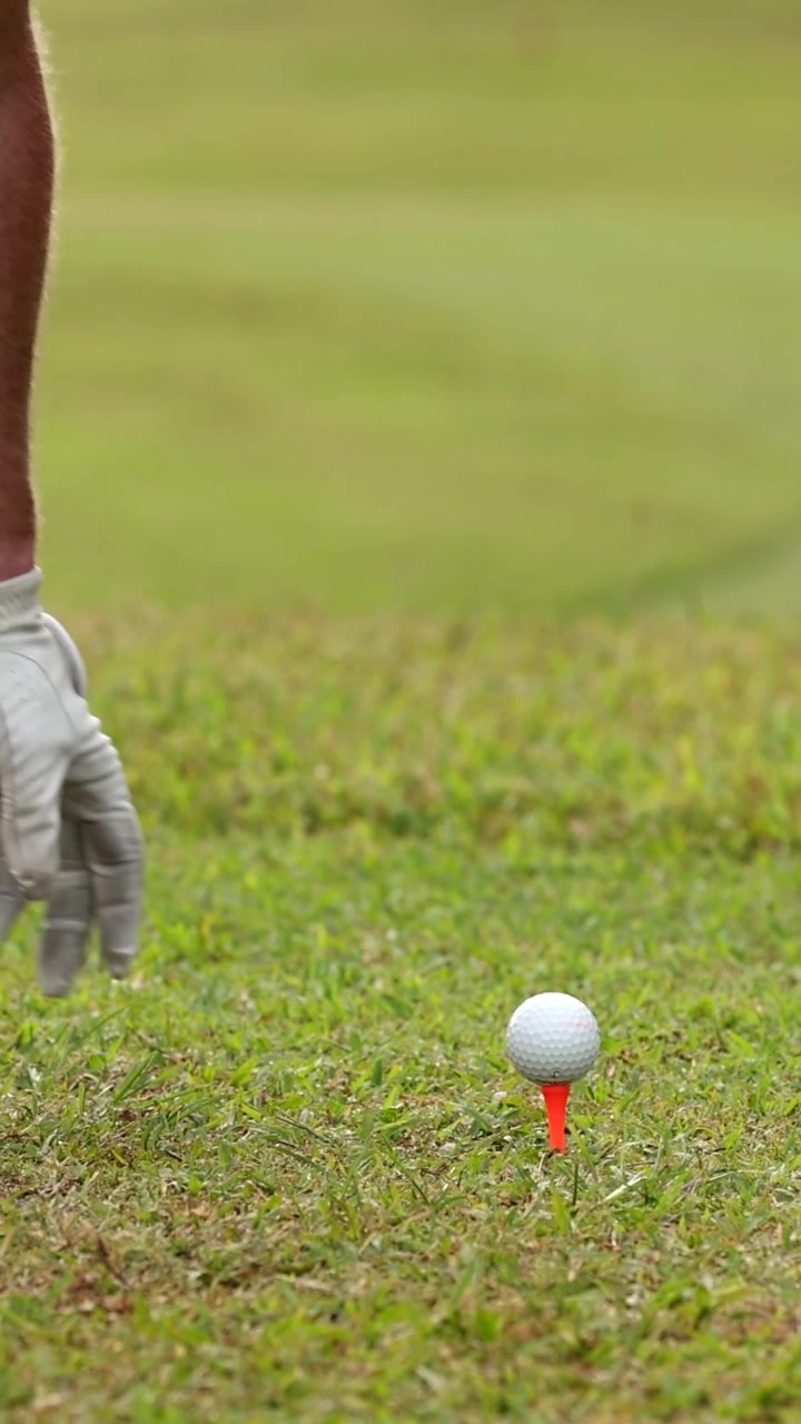 Golfista che posiziona attentamente la palla sul tee