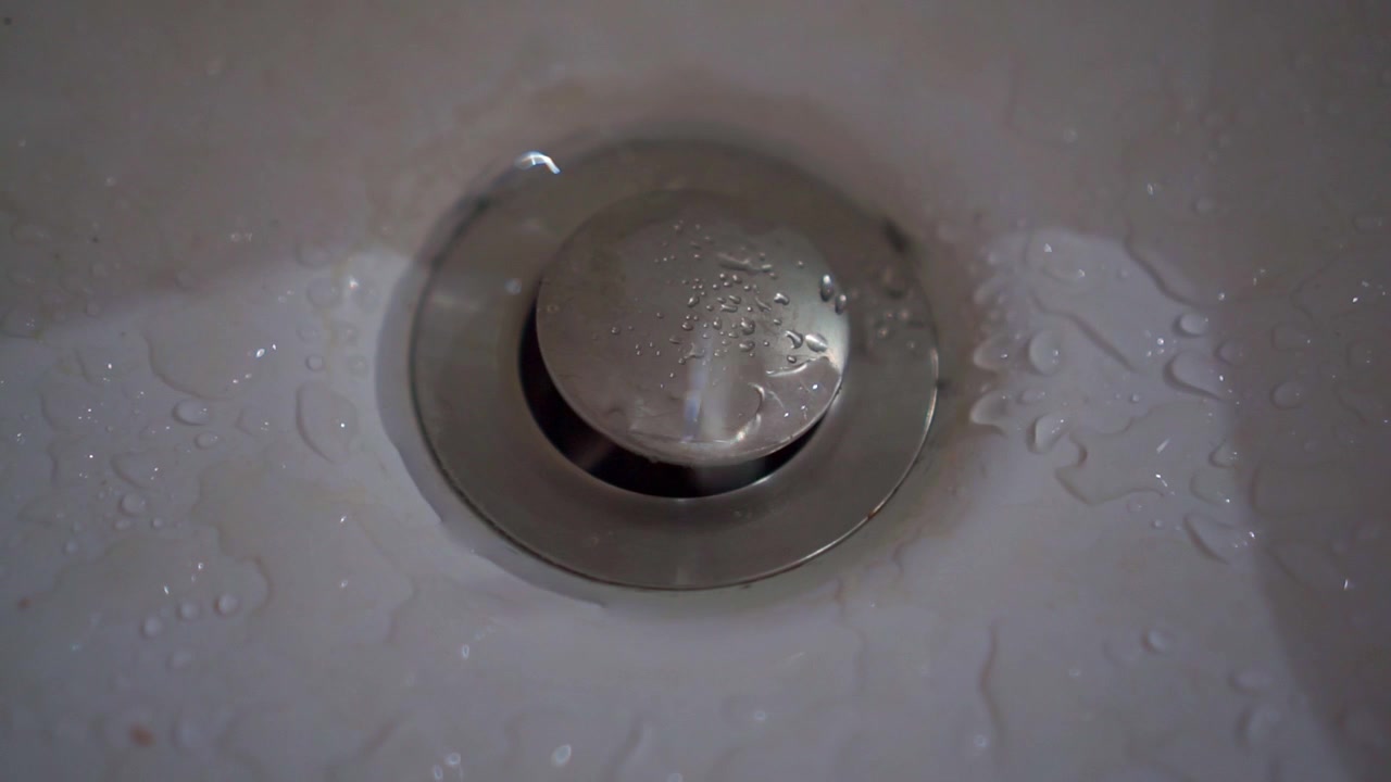 Gouttelettes d'eau sur un siphon d'évier en acier inoxydable, détail de plomberie de salle de bain, surface mouillée, séquence conceptuelle de nettoyage et d'hygiène.