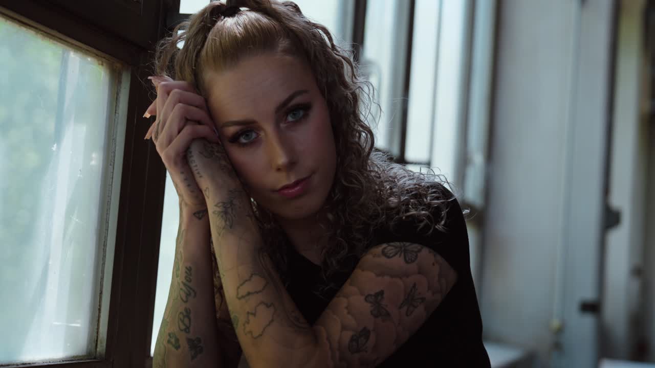 Thoughtful Tattooed Woman Staring into Camera in Natural Light, slow motion