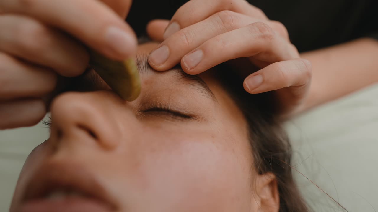 Nahaufnahme einer Frau bei einer entspannenden Gua Sha Gesichtsmassage
