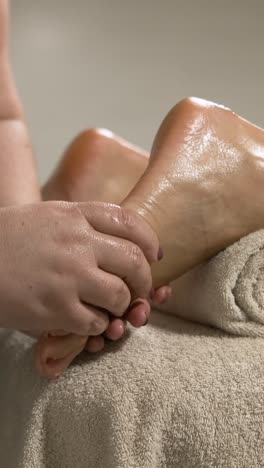 masseuse performing foot massage on client. vertical