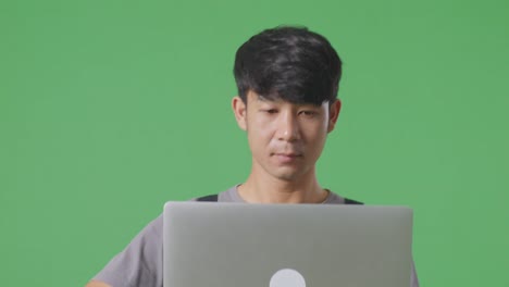 녹색 화면 배경 스튜디오에서 는 동안 노트북을 사용하는 아시아 남성 노동자의 근접