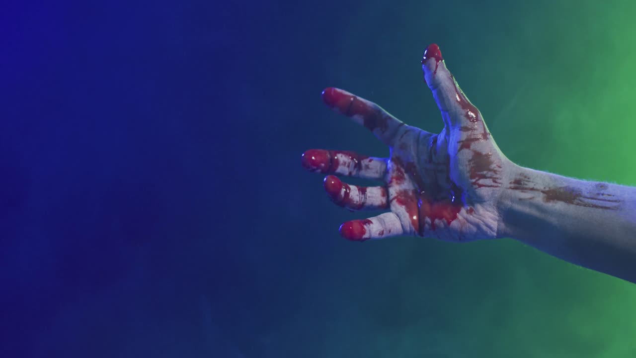 video de una mano cubierta de sangre moviéndose sobre humo sobre un fondo negro