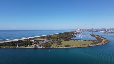 high static drone view of a popular beach and council infrastructure with an urban skyline city in the distance