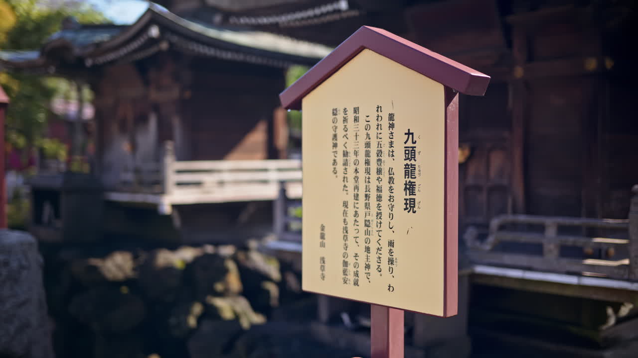 Close up of a wooden informational sign with a blurred background at the Senso-ji temple in Asakusa, Tokyo, Japan. Translation: "information about the Mitsumine Shrine"