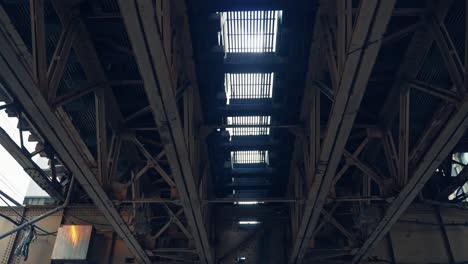 static upward view of elevated rail tracks as trams pass each other in chicago downtown
