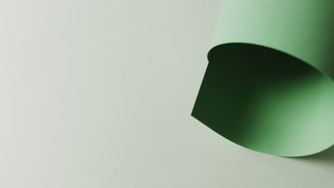 Close-up-of-green-rolled-piece-of-paper-on-white-background-with-copy-space-in-slow-motion