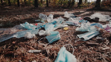 máscaras médicas y plástico en el suelo del bosque