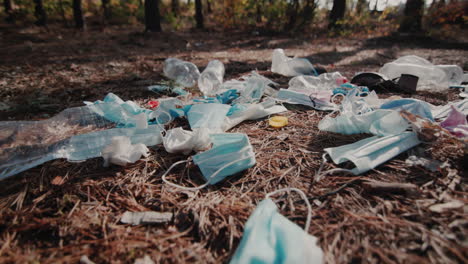 medical masks and plastic lies on the ground in the forest