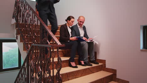 un hombre de negocios sobrecargado de trabajo leyendo un informe en las escaleras.