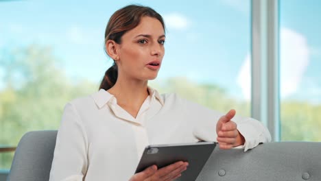 una mujer de negocios moderna en conversación con una tableta en la mano en un espacio de oficina moderno frente a una ventana