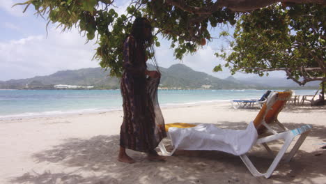 latin girl on exotic beach lies down to rest and relax on lounger in cool shade of tree