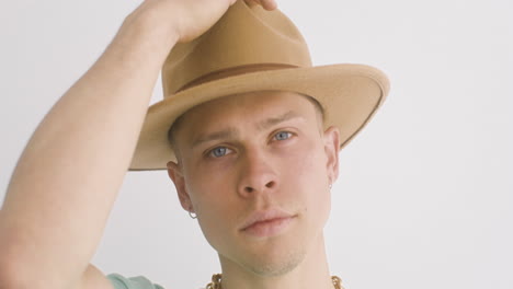 retrato de un joven poniéndose un sombrero, mira al frente y luego mueve la cabeza