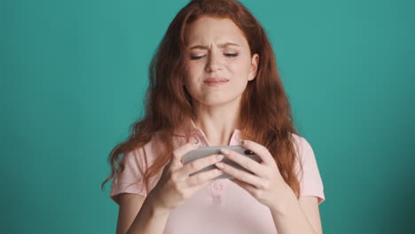 redheaded girl in front of camera on turquoise background.