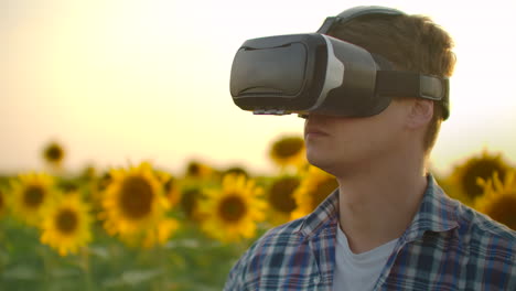 a modern farmer in a field with sunflowers uses virtual reality glasses and gestures to control the watering map and drones for the best harvest.