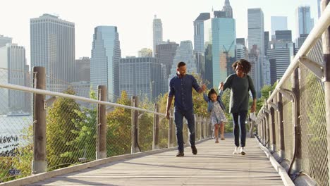 Black-couple-and-daughter-walking-on-footbridge-in-Manhattan