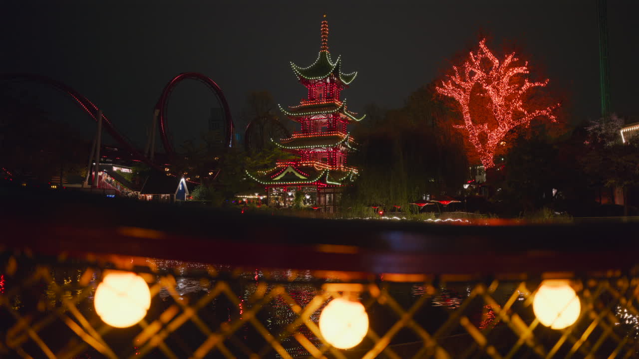 View of a lit pagoda and surrounding landscape in Tivoli Gardens, Copenhagen, Denmark, at night