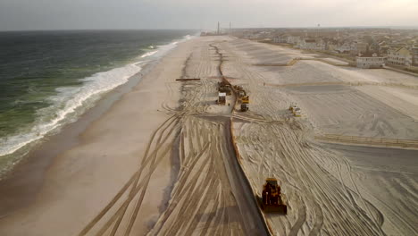 fast fly by aerial pull back of the large scale dredging operation of a long pipe laying along the beach spraying new sand and construction equipment redirecting it