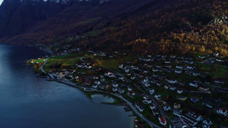 uniform white homes on high alpine river or lake coastline in shadows of mountains