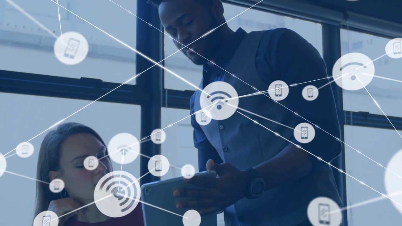 Standing man showing tablet initiating Wi-Fi icons filling screen peer leaning in working on tech