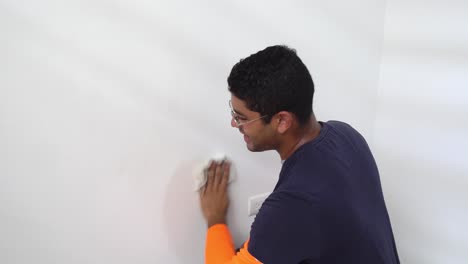 a man cleaning the interior wall of the house prior to painting it - static shot