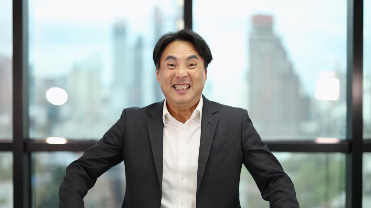 Smiling businessman in suit pumps fist in victory, bright office, cityscape background, natural lighting