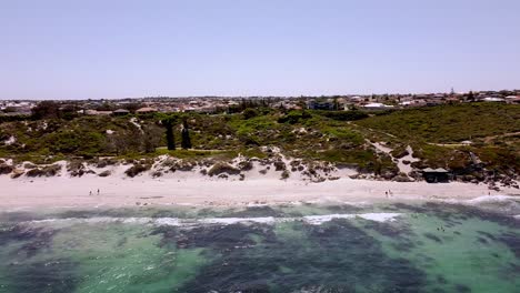 Panning-shot-right-to-left-of-coastline-and-people-on-white-sandy-beach