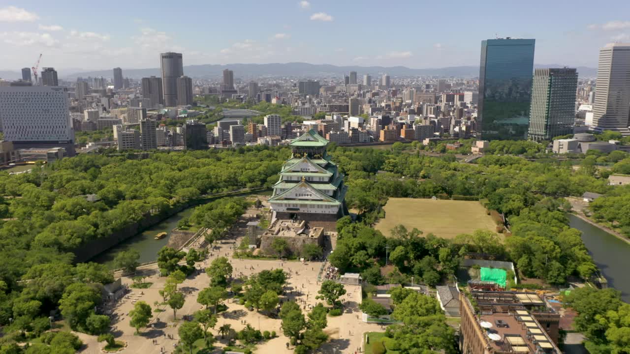 Aerial of historic landmark Osaka Castle with park, moat, skyscraper, and city in Osaka, Japan