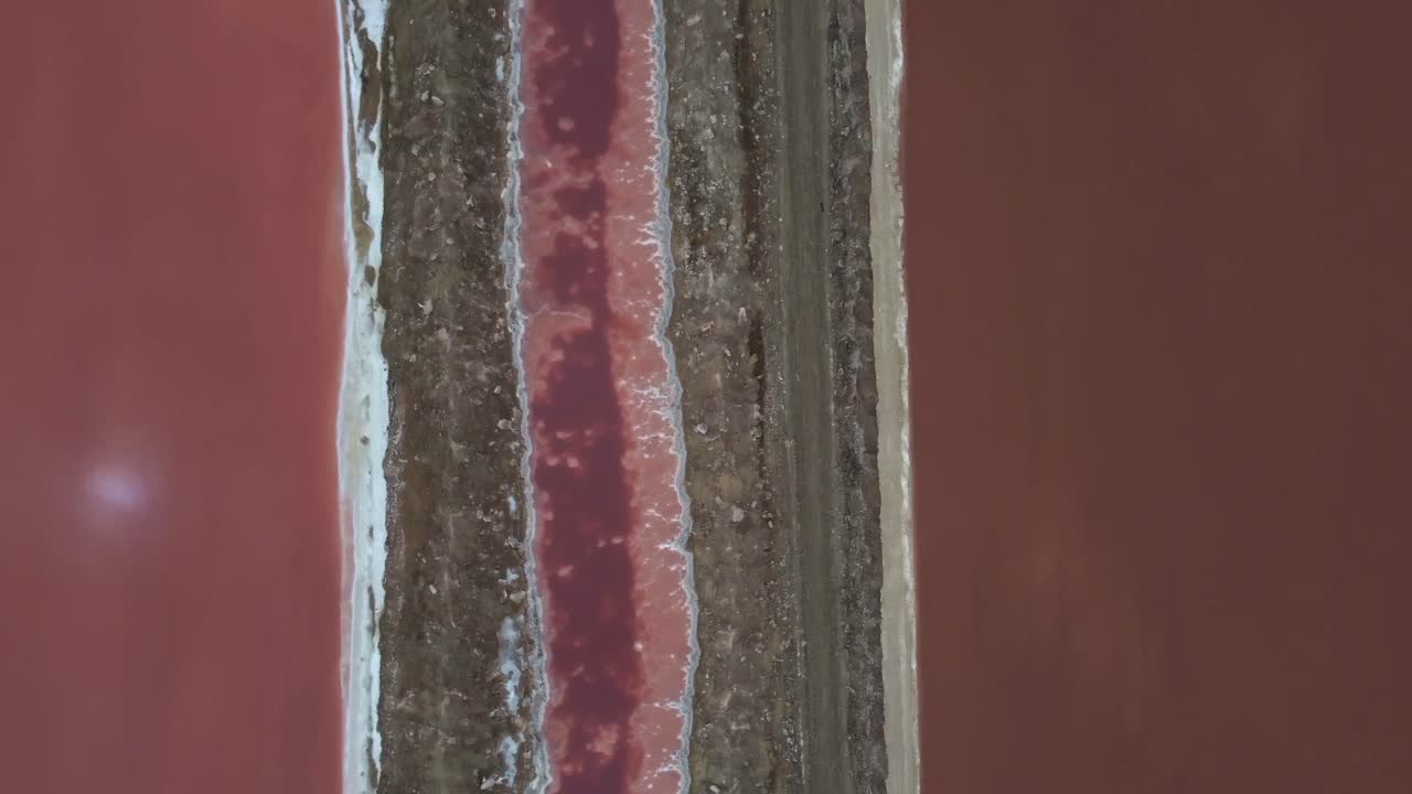 tiro de ojo de pájaro con dron de una mina de sal en namibia - dron está volando sobre lagos rosados y carreteras de transporte