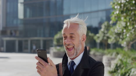 retrato feliz hombre de negocios maduro usando teléfono inteligente video chat agitando la mano disfrutando de la conversación hablando por teléfono móvil en la soleada ciudad urbana cámara lenta