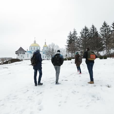 group of people walking in snowy landscape near a church