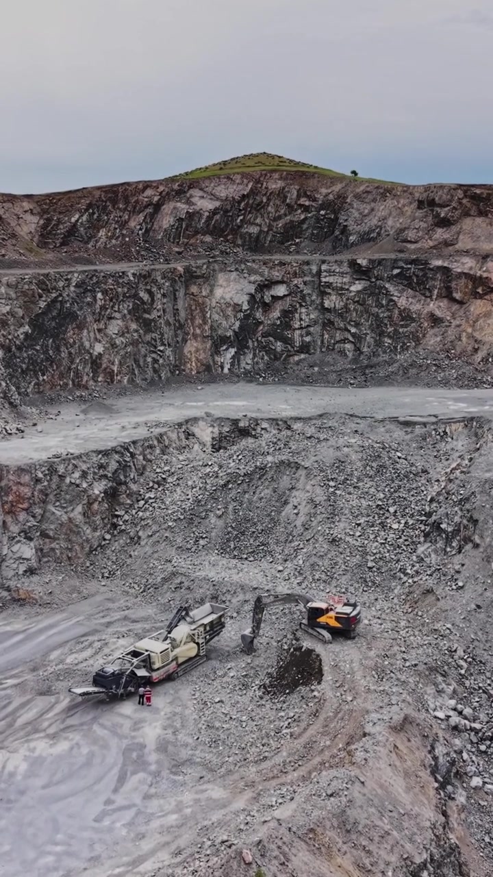 Heavy machinery works in a stone quarry near a river in daytime