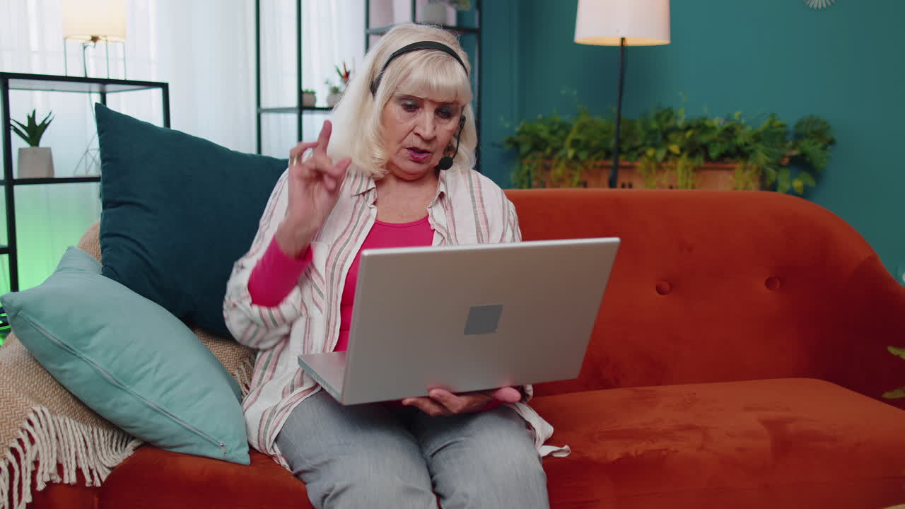 mujer senior independiente usar auriculares hacer llamadas de video hablar, enseñar en la computadora portátil en la oficina de casa
