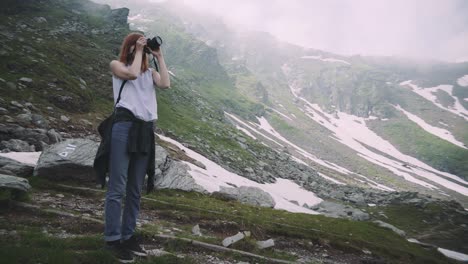 a young woman hiker climbs mountains with photo camera. transfagarasan, carpathian mountains in romania