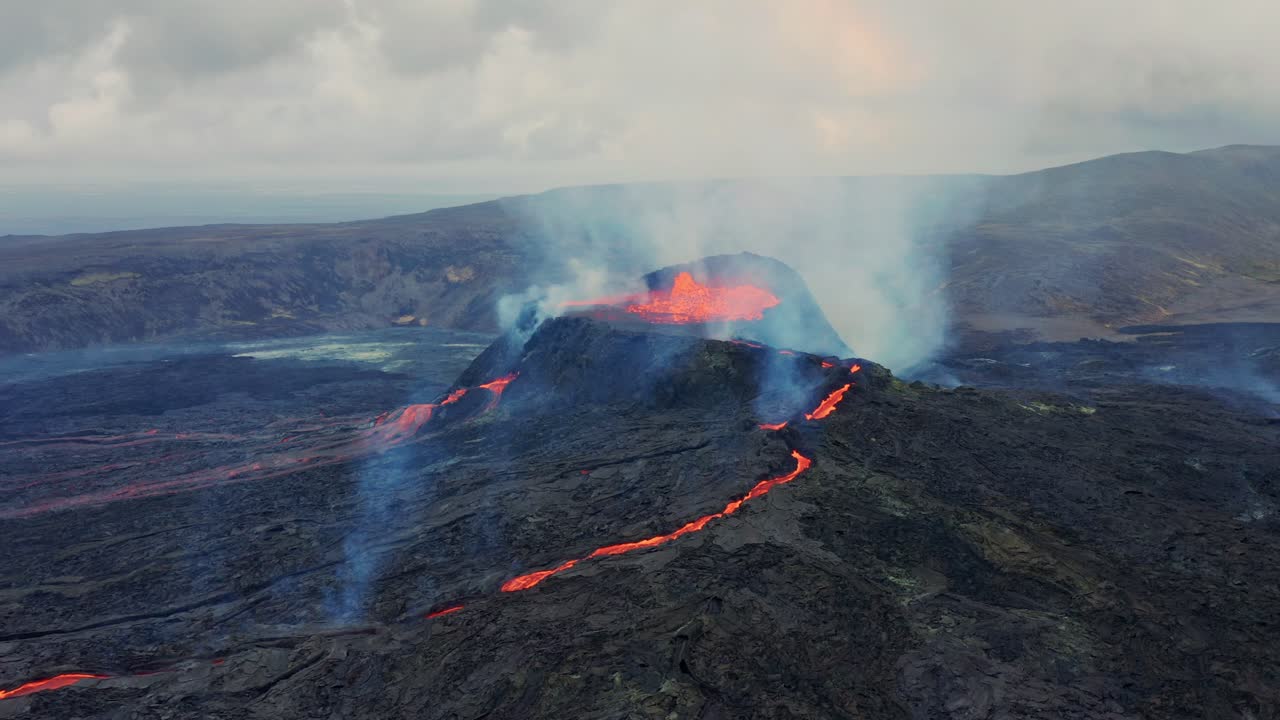 Sorvolando rocce laviche, avvicinandosi al vulcano attivo Fagradalsfjall con fiumi di lava che scendono dalla collina - Islanda.