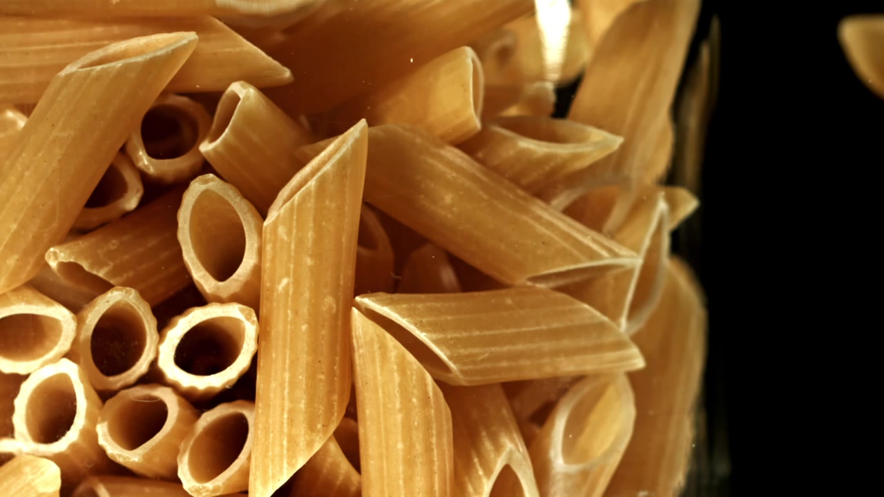 Penne secche che cadono in un contenitore al rallentatore