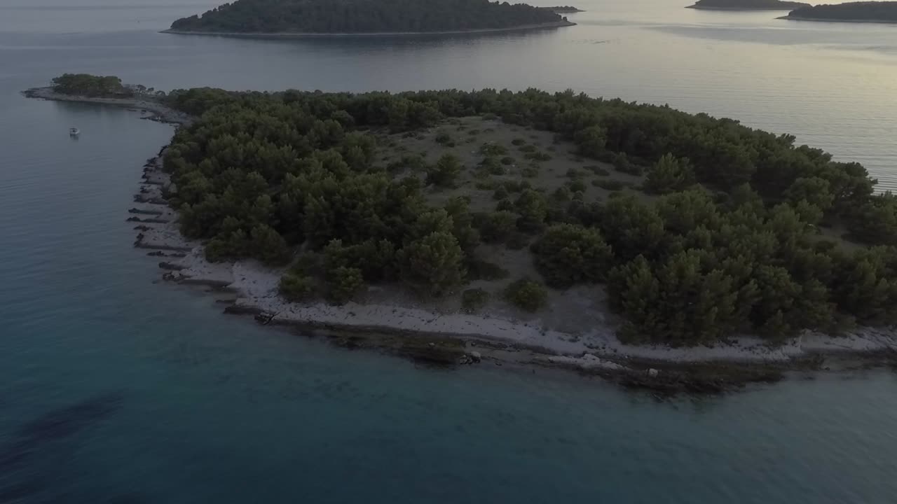Aerial orbit over Croatian island and shimmering sea at sunset