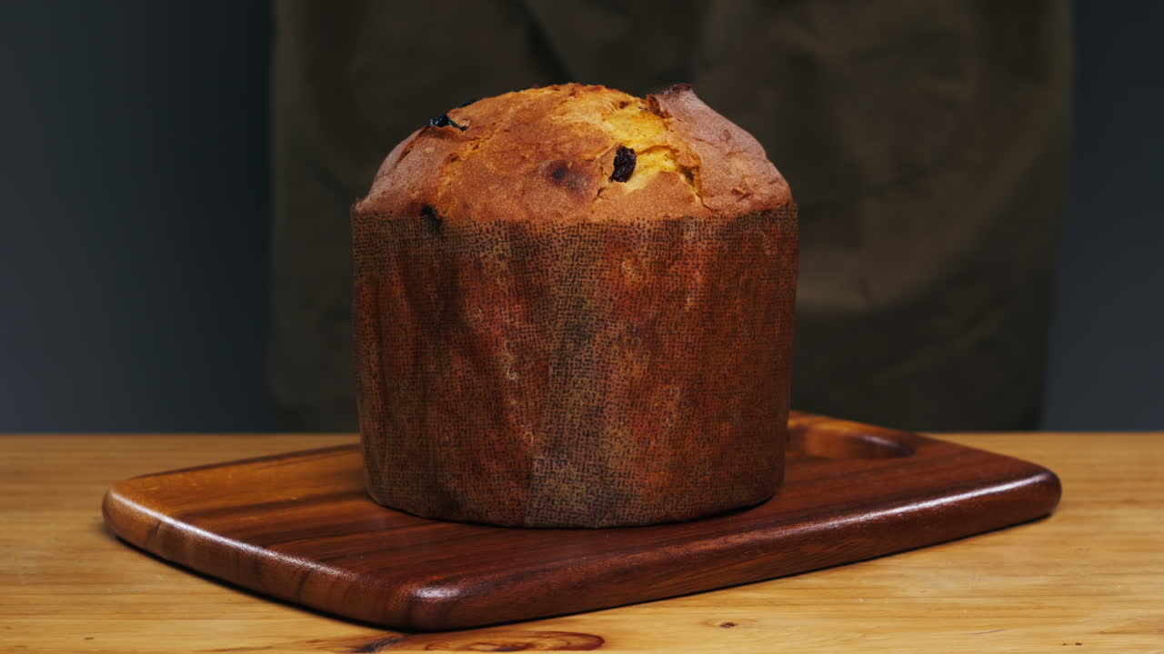 Traditional English Christmas cake tied with a jute thread on the black background. Italian classic Panettone .Pastry Chef sprinkles powdered sugar through a sieve on the fruit Easter cake with raisins. High quality 4k footage