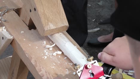 a child like a traditional carpenter with a metal planer peeling wood