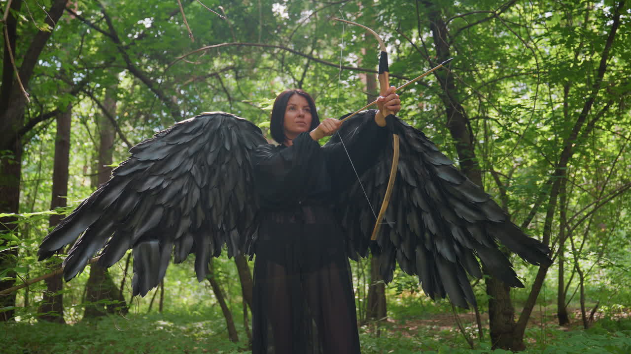 Huntress with black wings stands in glowing forest, drawing bow with elegant poise, soft sunlight wrapping her silhouette, revealing leg and strength, cinematic fantasy moment of beauty