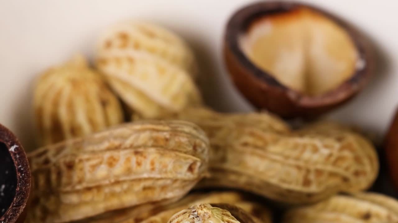 Vista detalhada de amendoins e cascas vazias dispostos próximos, destacando a textura e os padrões naturais.