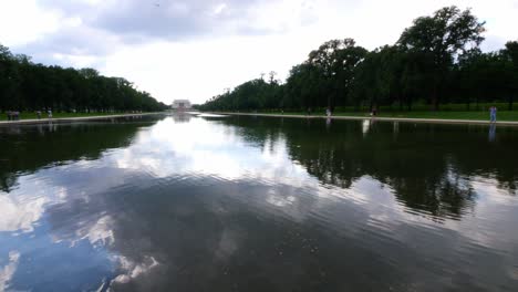 Blick-Vom-Wasser-Auf-Die-Vorderstufen-Des-Lincoln-Memorial,-Aufgenommen-Vom-Reflexionsteich-Mit-Menschen-Im-Vordergrund