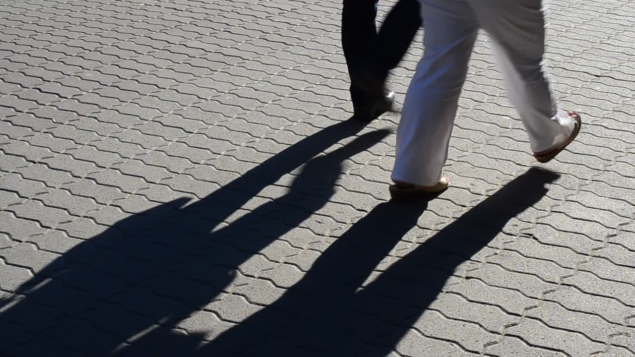 Light and shade, reflection of people in beams of the setting sun. Movement of group of people