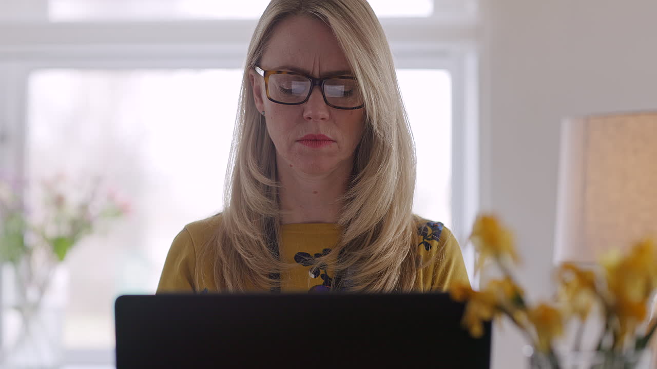 Woman working on laptop with flowers in the background