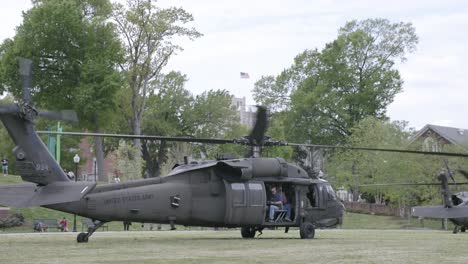 blackhawk helicopter on the ground with it's rotors spinning, ready for takeoff