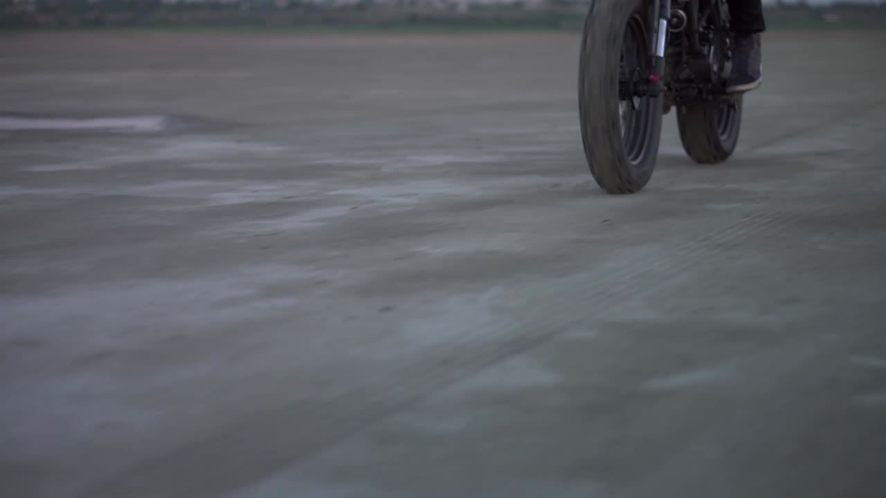Close up of biker's ride on black sport bike with switched front headlight by sandy ground