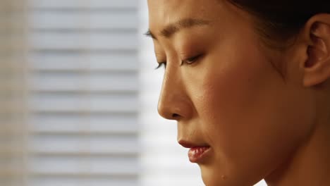 introspective moments: a close-up of a woman in thought, capturing subtle emotions and contemplation against a soft, blurred background of vertical blinds