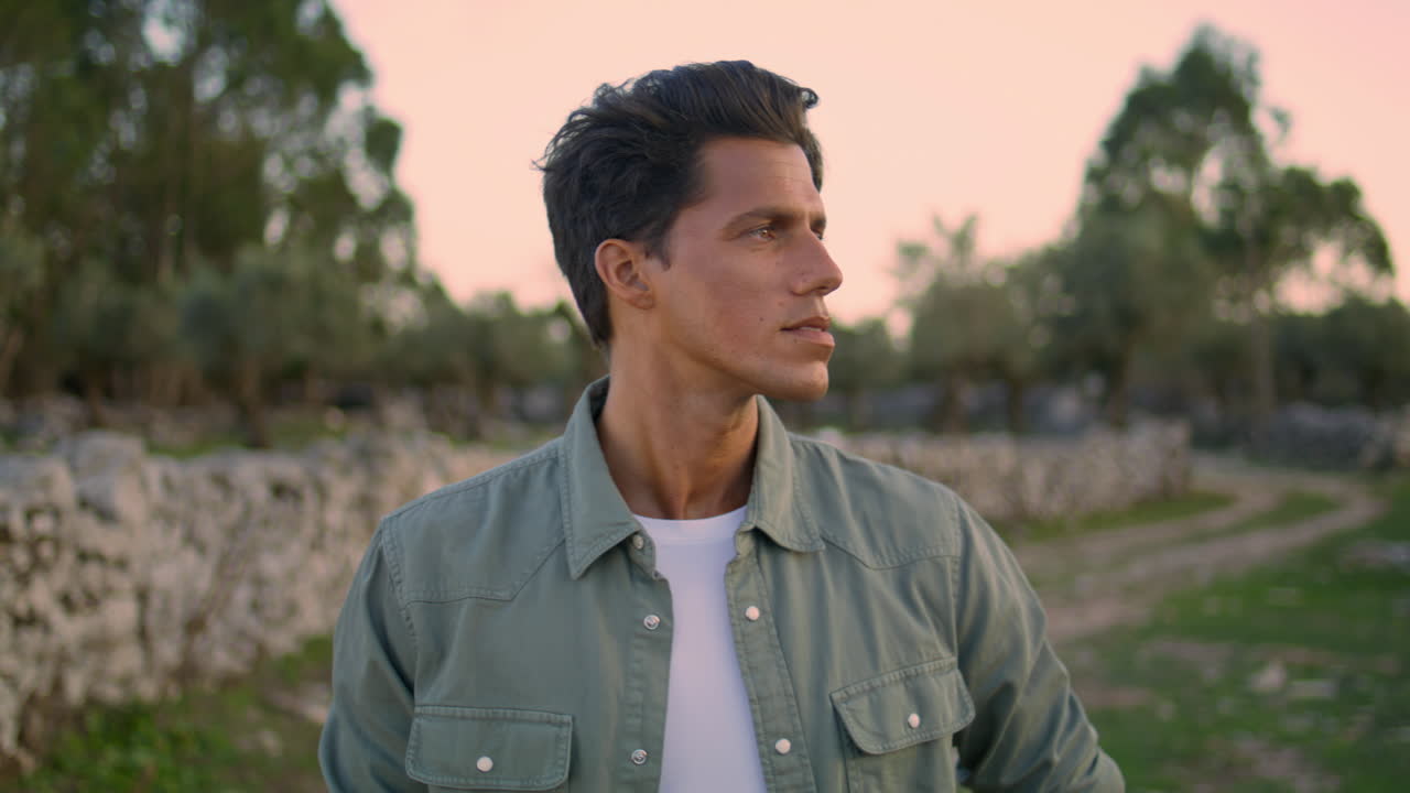 긍정적 인 남자 는 시골 곳 에서 카메라 를 포즈 를 취 하고 있다. 자연 을 향해 수직 으로 미소 짓는 남자